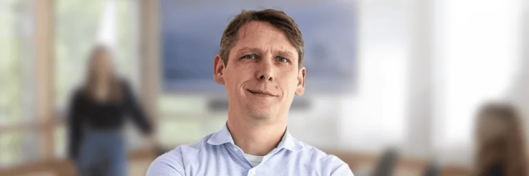 Andrej Teterin steht lächelnd im Raum und der Hintergrund ist geblurrt
