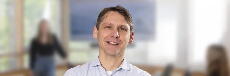 Andrej Teterin steht lächelnd im Raum und der Hintergrund ist geblurrt